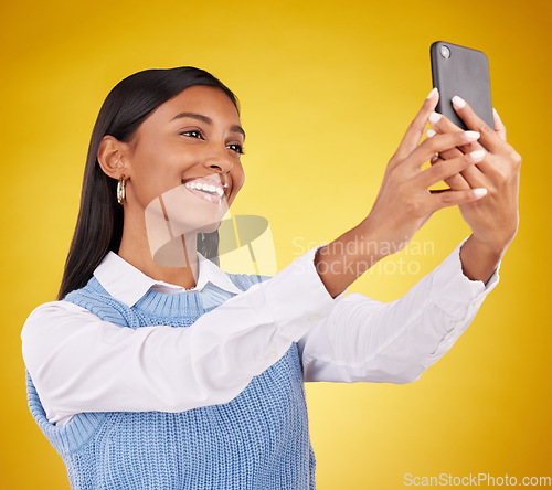 Image of Happy, smile and selfie with woman in studio for social media, technology and internet post. App, online and picture with female on yellow background for happiness, connection and photography