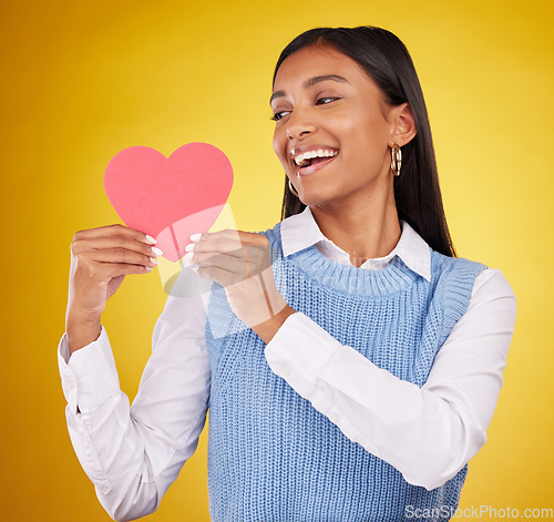 Image of Happy, paper and heart with woman in studio for love, support and romance. Valentines day, kindness and date with female and holding symbol on yellow background for health, happiness and hope