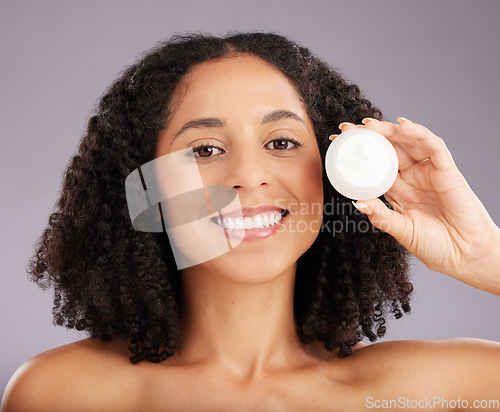 Image of Happy woman, face and portrait smile for moisturizer, beauty or skincare against a gray studio background. Female smiling with teeth holding cosmetic product for healthy skin or soft facial treatment