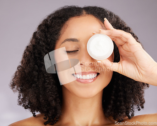 Image of Happy woman, face and smile for skincare moisturizer or beauty against a gray studio background. Female smiling with teeth holding cosmetic product for healthy skin, self care or facial treatment