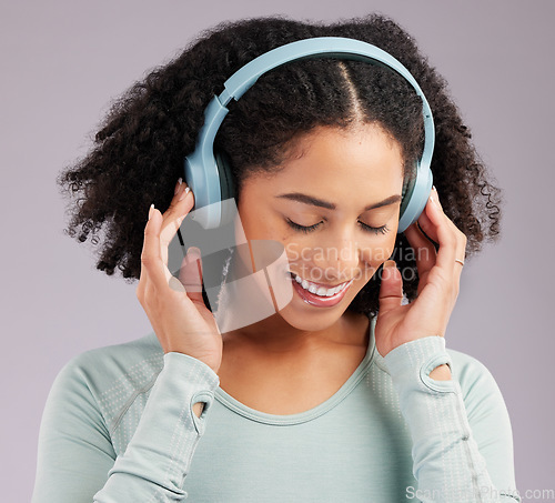Image of Woman, headphones and smile listening to music in joy against a gray studio background. Happy and fun female model smiling and relaxing in happiness with headset for audio track, sound or podcast