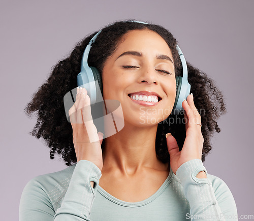 Image of Happy woman, headphones and smile listening to music in joy against a gray studio background. Fun and calm female smiling and relaxing in happiness with headset for audio track, sound or podcast