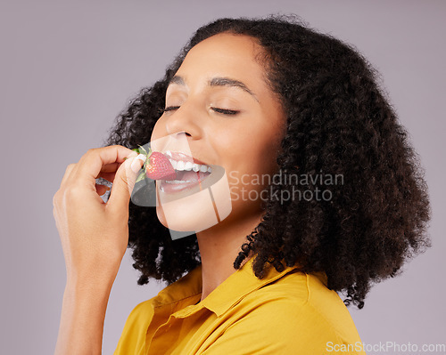 Image of Woman, face and eating strawberry for natural nutrition, dieting or healthy food against a gray studio background. Happy female smiling and enjoying tasty organic fruit for health, diet or wellness