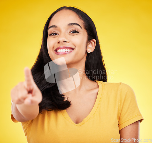 Image of Pointing, happy and portrait of a woman in a studio with a smile and positive face expression. Happiness, finger and female model from Puerto Rico with a showing hand gesture by a yellow background.