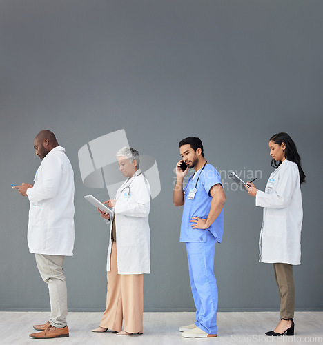 Image of Doctors standing in a row isolated on wall background with tablet, phone call and medical paperwork for hospital. Healthcare people or nurse technology in waiting room for clinic or hiring research