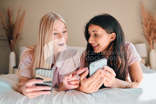 Image of Wow, happy and women with a phone on a bed for social media, communication and notification. Shock, smile and friends reading news, message or online chat on a mobile during a sleepover together