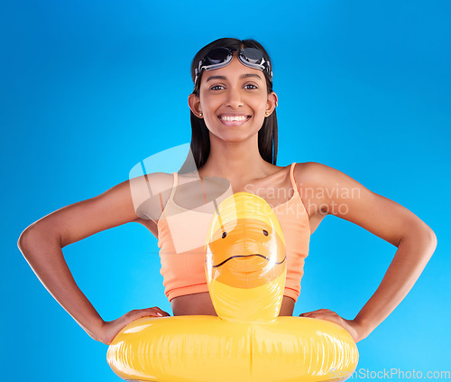 Image of Happy, pool float and portrait of woman in studio for summer, swimming and holiday. Smile, happiness and beach vacation with female and duck inflatable on blue background safety, playful and funny