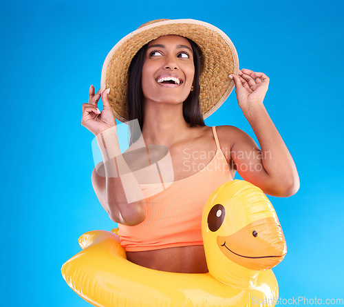 Image of Thinking, hat and rubber duck with a woman on a blue background in studio ready for summer swimming. Happy, travel and vacation with an attractive young female looking excited to relax or swim
