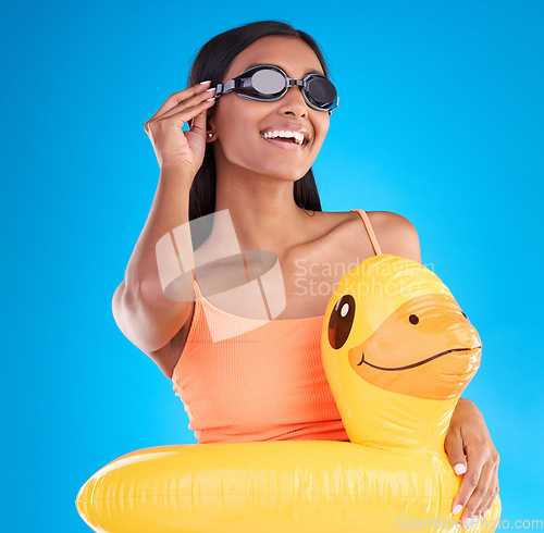 Image of Goggles, smile and rubber duck with a woman on a blue background in studio ready for summer swimming. Happy, travel and vacation with an attractive young female looking excited to relax or swim