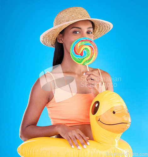 Image of Portrait, lollipop and rubber duck with a woman on a blue background in studio ready for summer swimming. Happy, travel and vacation with an attractive young female looking excited to relax or swim