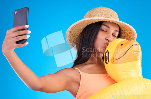 Image of Happy woman, selfie and swimming travel for social media or profile picture with inflatable duck against a blue studio background. Excited female model in summer swimwear for photo, vacation or trip