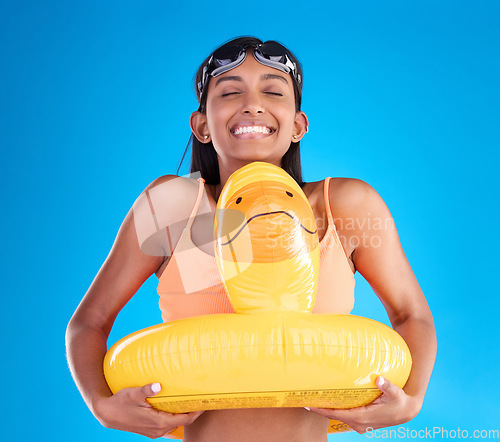 Image of Smile, goggles and rubber duck with a woman on a blue background in studio ready for summer swimming. Happy, travel and vacation with an attractive young female feeling excited to relax or swim