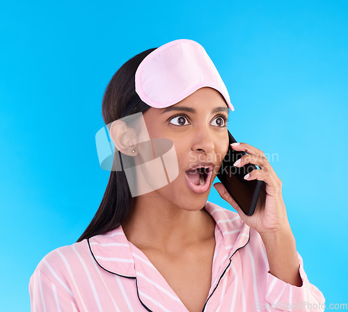 Image of Phone call, shock and woman in pajamas in a studio with shocking, winning or good news. Surprise, happy and Indian female model on a mobile conversation with a wtf, omg or wow face by blue background