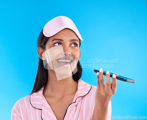 Image of Woman in pajamas, smartphone and phone call on speaker, conversation and smile against a blue studio background. Female, cellphone and girl in sleepwear, chatting and communication with joy and plans