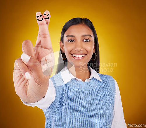 Image of Smiley face, fingers crossed and portrait of Indian woman in studio with drawing for hand sign, symbol and luck. Emoji mockup, yellow background and happy girl smile for wish, hope and lucky gesture