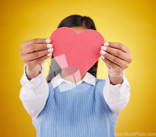 Image of Cover, paper and heart with woman in studio for love, support and romance. Valentines day, kindness and date with female hiding with symbol on yellow background for health, happiness and hope mockup