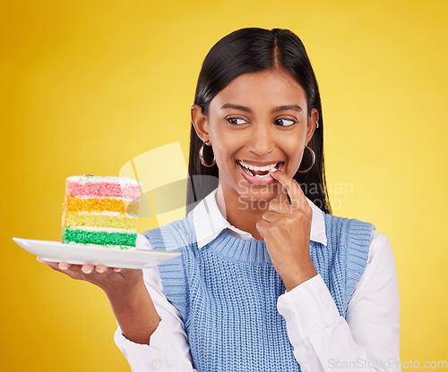 Image of Birthday, diet and woman with cake in studio for happy celebration or party on yellow background. Happiness, excited gen z model with rainbow dessert on plate to celebrate milestone or achievement.