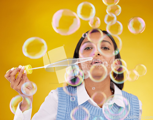 Image of Portrait, fun and woman blowing bubbles, positive attitude and cheerful against a studio background. Face, female and lady with soap bubble, excitement and joyful with wellness, break and playful