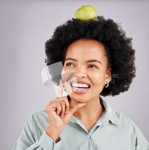 Image of Thinking, apple on head and black woman with happiness, wellness and health on a grey studio background. African American female, fruit and lady with ideas, planning diet and wellness with body care
