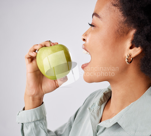 Image of Apple, health and black woman in studio eating for nutrition, wellness and healthy snack. Food, diet and face profile of girl eat green fruit for detox, vitamins and weight loss on white background