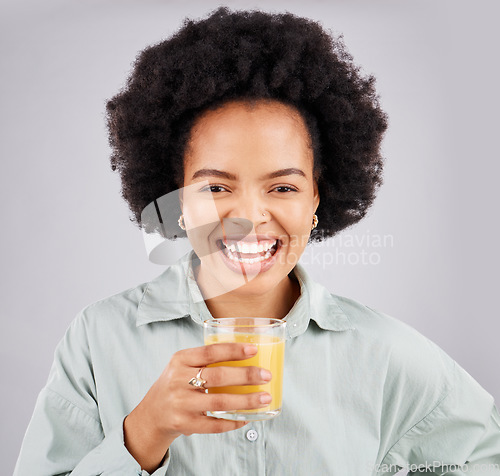 Image of Portrait, smile and orange juice with a laughing woman in studio on a gray background for health or vitamin c. Face, drink and glass with a happy young female drinking a fresh beverage for nutrition