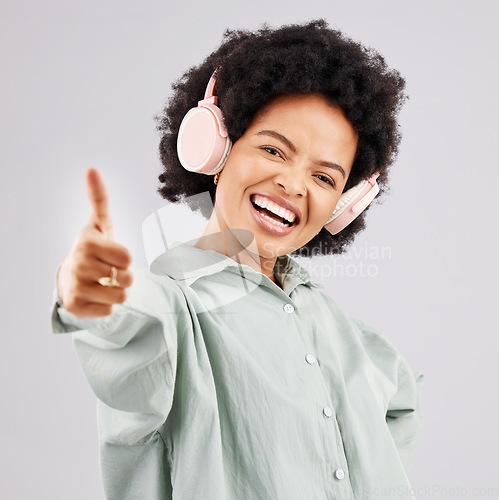 Image of Portrait, thumbs up and black woman with headphones in studio isolated on a white background. Success, funny and person with hand gesture, emoji or winning, agreement or like while streaming music.