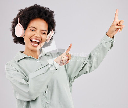 Image of Portrait, music headphones and black woman pointing up in studio isolated on a white background mockup or advertising space. Singer, radio and happiness of person listening to audio, sound or podcast