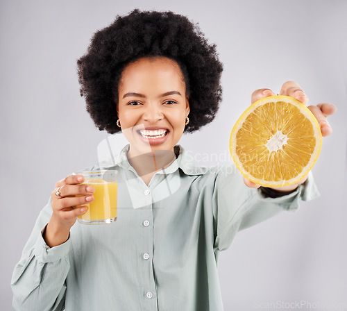 Image of Portrait, orange and juice with a woman, happy in studio on a gray background for health or vitamin c. Face, drink and fruit with a young female drinking a fresh beverage in a glass for nutrition