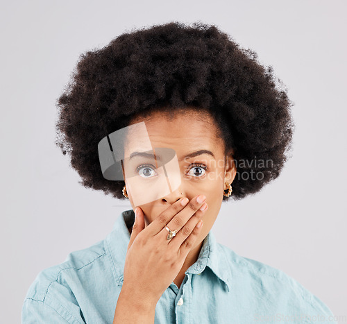 Image of Portrait, hand and mouth with a surprised woman in studio on a gray background feeling shocked by gossip. Face, wow or afro and a young female hearing news with an omg or wtf expression of disbelief