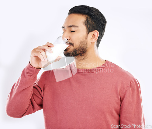 Image of Man drinking glass of milk in studio, white background and backdrop for healthy dairy, smoothies and diet. Male model, cup and calcium of smoothie, vanilla milkshake and nutrition of protein drink