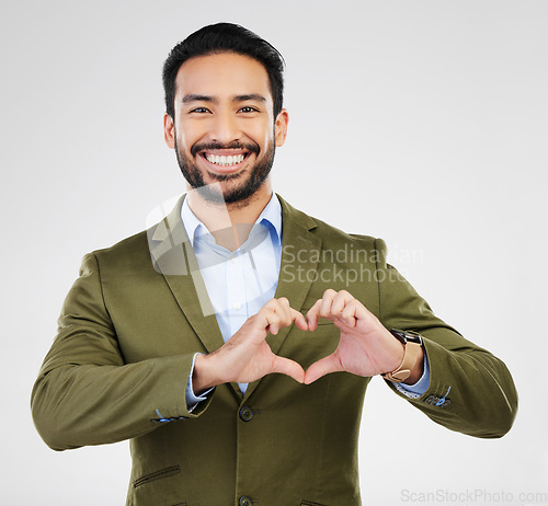 Image of Portrait, heart and hand gesture with a business man in studio on a gray background for health or love. Hands, emoji and shape with a happy male employee showing a symbol or sign of affection