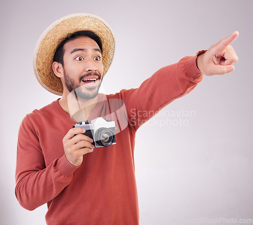 Image of Travel, camera and surprise, man pointing on holiday, adventure and mockup on white background. Smile, point and photographer in studio showing gesture of shock on vacation with discovery on journey.