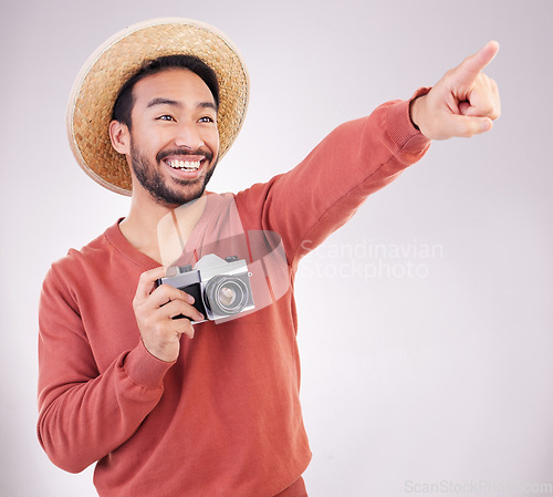 Image of Travel, camera and excited man pointing at view in studio on holiday with adventure, fun and white background. Smile, discovery and happy tourist on vacation, photographer on journey with happiness.