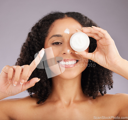 Image of Woman, face and smile for skincare cream or beauty against a gray studio background. Portrait of happy female smiling and holding cosmetic product in healthy skin, self care or facial treatment