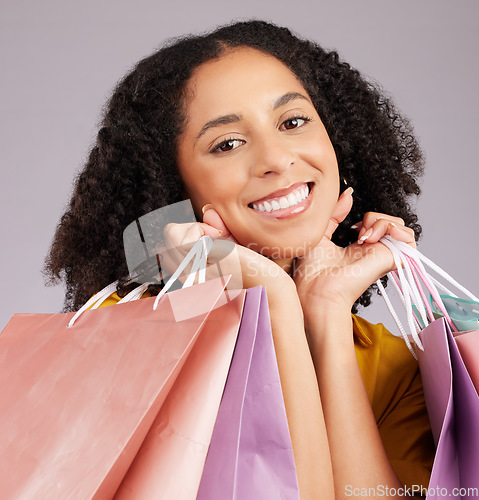 Image of Happy woman, face and portrait smile with shopping bags for discount, sale or fashion against gray studio background. Female shopper smiling and holding gifts or shop accessories posing in happiness