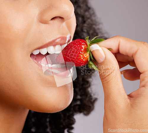 Image of Woman, mouth and eating strawberry for natural nutrition, dieting or healthy food against a gray studio background. Closeup of female lips enjoying tasty organic fruit for health, diet or wellness