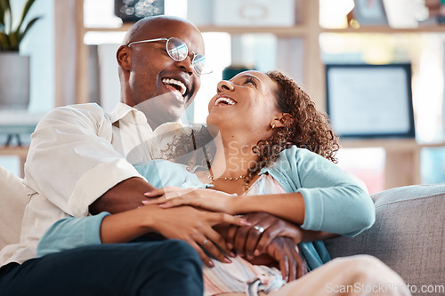 Image of Love, happy and couple laugh on sofa for bonding, quality time and relaxing together at home. Marriage, relationship and black man and woman on couch embrace, hugging and laughing for funny joke