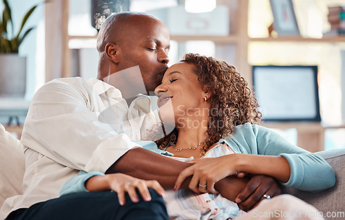 Image of Love, kiss and couple relax on sofa for bonding, quality time and happiness together at home. Marriage, relationship and interracial man and woman on couch for calm, romance and embrace on weekend