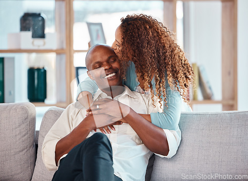 Image of Love, happy and couple kiss on sofa for bonding, quality time and relaxing together at home. Marriage, interracial relationship and man and woman on couch embrace, hugging and laughing in living room