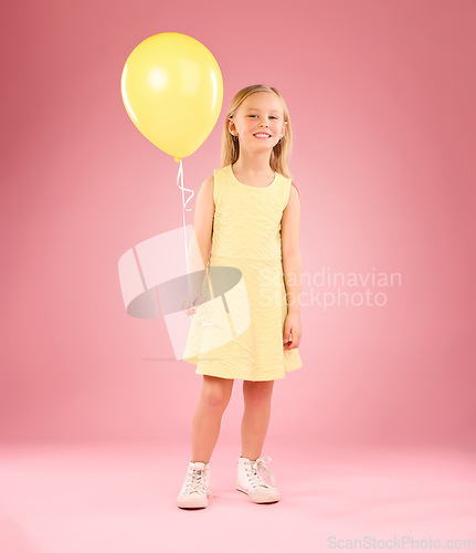 Image of Girl, child and portrait with a balloon in studio on a pink background with smile. Female kid model with happiness, creativity and yellow birthday party decoration in hand isolated on color and space