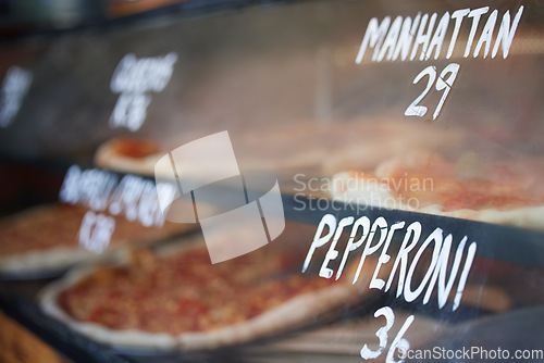 Image of Storefront, pizza and fast food price, service and take away restaurant with closeup, shop display and window. Words, nutrition at cafe or bakery, lunch or dinner with to go meal option in New York