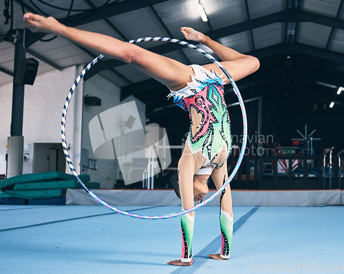 Image of Sports, gymnastics and woman with a hula hoop for a performance in a professional arena. Fitness, rhythm and female athlete or gymnast doing a flexibility and strength trick training for competition.