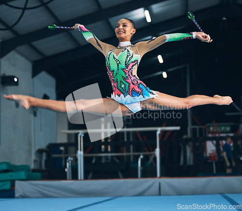 Image of Sports, gymnastics and woman jumping with a ribbon in a professional gym or arena for training. Fitness, routine and female athlete gymnast doing a trick while practicing for competition or challenge