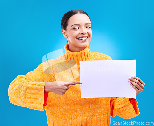 Image of Poster, point and portrait of woman on blue background for announcement, news and information. Advertising, mockup studio and isolated happy girl with paper sign for brand, logo and product placement