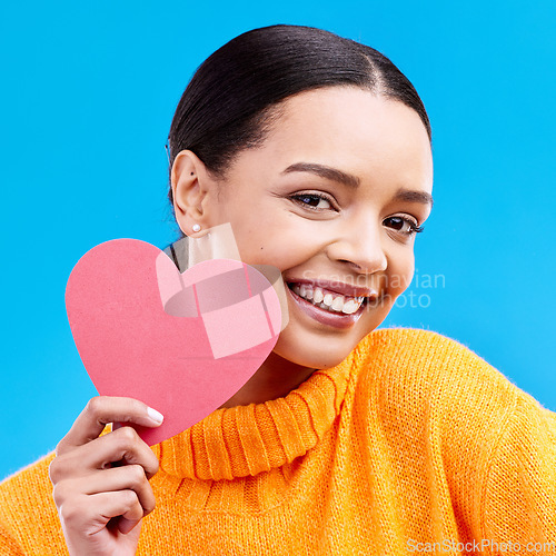 Image of Paper heart, love and portrait of happy woman in studio, blue background and romantic sign. Female model, emoji shape and smile for care, support and thank you for kindness, valentines day or emotion