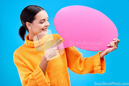 Image of Speech bubble, smile and woman pointing to banner in studio for advertising on blue background. Happy, finger and female with poster, mockup and space for social media, announcement or billboard news