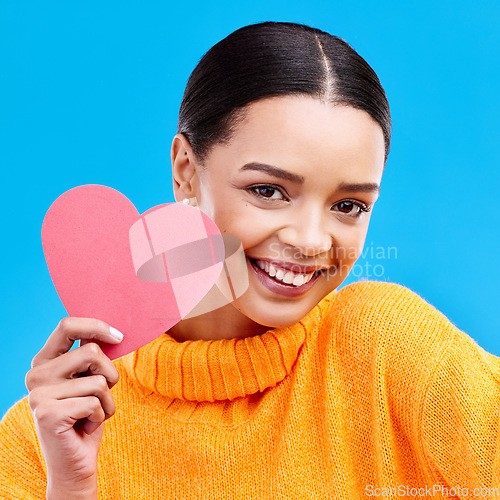 Image of Paper heart, smile and portrait of woman in studio, blue background and backdrop. Happy female model, love shape and care of trust, support and thank you for kindness, valentines day and emoji icon