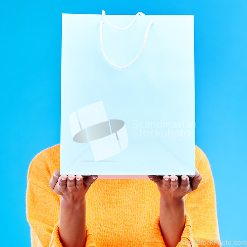 Image of Shopping, bag and hands of woman on blue background for retail discount, deal and store promotion. Commerce mockup, fashion and girl holding package for advertising, sale news and purchase in studio