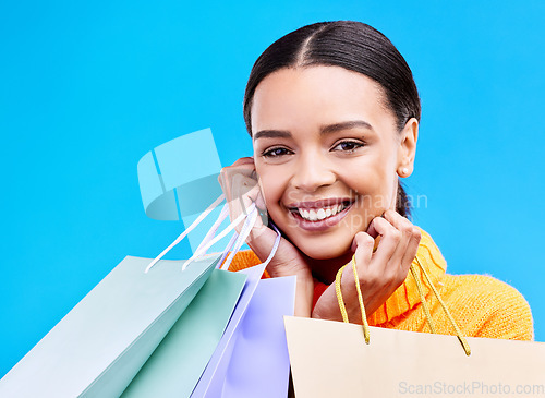 Image of Shopping bags, studio and woman portrait with a smile and happiness from boutique sale. Happy, customer and female model with store bag and sales choice in isolated blue background with young person