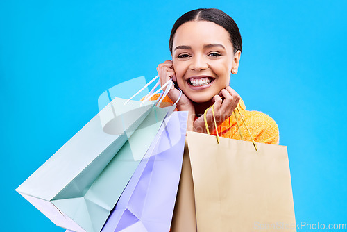 Image of Shopping bags, excited and woman portrait with a smile and happiness from boutique sale. Happy, customer and female model with store bag and sales choice in isolated blue background and studio